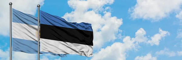 Arjantin ve Estonya bayrağı birlikte beyaz bulutlu mavi gökyüzüne karşı rüzgarsal sallayarak. Diplomasi kavramı, uluslararası ilişkiler. — Stok fotoğraf