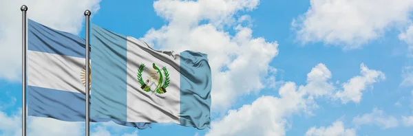 Argentinien und Guatemala schwenken gemeinsam die Flagge im Wind vor dem wolkenverhangenen blauen Himmel. Diplomatie-Konzept, internationale Beziehungen. — Stockfoto