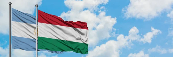 Argentina e Ungheria bandiera sventolando nel vento contro bianco cielo blu nuvoloso insieme. Concetto di diplomazia, relazioni internazionali . — Foto Stock