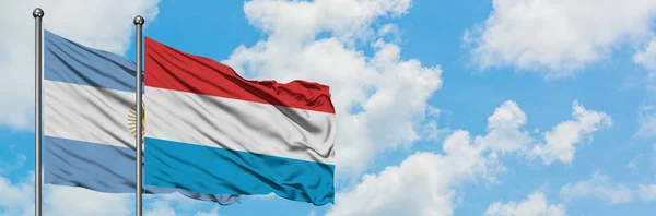Argentina e Lussemburgo sventolano insieme la bandiera contro il bianco cielo azzurro nuvoloso. Concetto di diplomazia, relazioni internazionali . — Foto Stock
