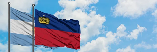 Bandera de Argentina y Liechtenstein ondeando en el viento contra el cielo azul nublado blanco juntos. Concepto diplomático, relaciones internacionales . — Foto de Stock