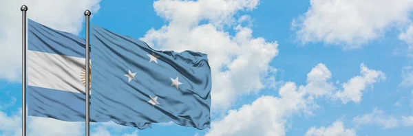 Argentinien und Mikronesien schwenken gemeinsam die Flagge im Wind gegen den wolkenverhangenen blauen Himmel. Diplomatie-Konzept, internationale Beziehungen. — Stockfoto