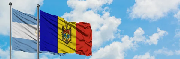 Bandera de Argentina y Moldavia ondeando en el viento contra el cielo azul nublado blanco juntos. Concepto diplomático, relaciones internacionales . — Foto de Stock