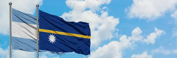 Bandera de Argentina y Nauru ondeando en el viento contra el cielo azul nublado blanco juntos. Concepto diplomático, relaciones internacionales . — Foto de Stock