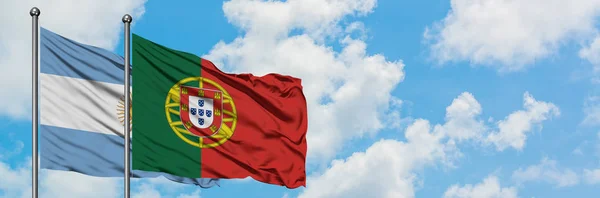 Bandeira da Argentina e de Portugal agitando no vento contra o céu azul nublado branco juntos. Conceito de diplomacia, relações internacionais . — Fotografia de Stock