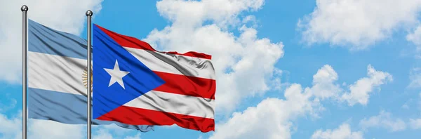 Arjantin ve Porto Riko bayrağı birlikte beyaz bulutlu mavi gökyüzüne karşı rüzgarda sallayarak. Diplomasi kavramı, uluslararası ilişkiler. — Stok fotoğraf