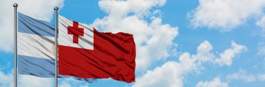 Arjantin ve Tonga bayrağı birlikte beyaz bulutlu mavi gökyüzüne karşı rüzgarda sallayarak. Diplomasi kavramı, uluslararası ilişkiler.