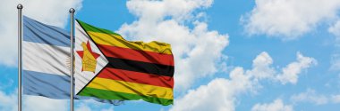 Arjantin ve Zimbabve bayrağı birlikte beyaz bulutlu mavi gökyüzüne karşı rüzgarsal sallayarak. Diplomasi kavramı, uluslararası ilişkiler.