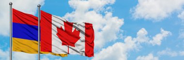 Ermenistan ve Kanada bayrağı birlikte beyaz bulutlu mavi gökyüzüne karşı rüzgarda sallayarak. Diplomasi kavramı, uluslararası ilişkiler.