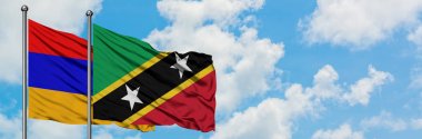 Ermenistan ve Saint Kitts ve Nevis bayrağı birlikte beyaz bulutlu mavi gökyüzüne karşı rüzgarda sallayarak. Diplomasi kavramı, uluslararası ilişkiler.