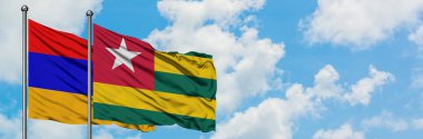 Ermenistan ve Togo bayrağı birlikte beyaz bulutlu mavi gökyüzüne karşı rüzgarda sallayarak. Diplomasi kavramı, uluslararası ilişkiler.