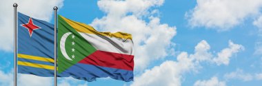Aruba ve Komorbayrağı birlikte beyaz bulutlu mavi gökyüzüne karşı rüzgarda sallayarak. Diplomasi kavramı, uluslararası ilişkiler.