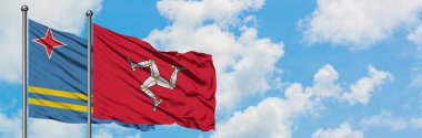 Aruba ve Isle Of Man bayrağı birlikte beyaz bulutlu mavi gökyüzüne karşı rüzgarda sallayarak. Diplomasi kavramı, uluslararası ilişkiler.