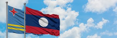 Aruba ve Laos bayrağı birlikte beyaz bulutlu mavi gökyüzüne karşı rüzgarda sallayarak. Diplomasi kavramı, uluslararası ilişkiler.