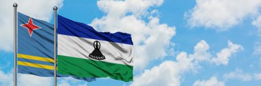 Aruba ve Lesotho bayrağı birlikte beyaz bulutlu mavi gökyüzüne karşı rüzgarda sallayarak. Diplomasi kavramı, uluslararası ilişkiler.