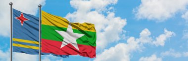 Aruba ve Myanmar bayrağı birlikte beyaz bulutlu mavi gökyüzüne karşı rüzgarda sallayarak. Diplomasi kavramı, uluslararası ilişkiler.