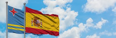 Aruba ve İspanya bayrağı birlikte beyaz bulutlu mavi gökyüzüne karşı rüzgarda sallayarak. Diplomasi kavramı, uluslararası ilişkiler.