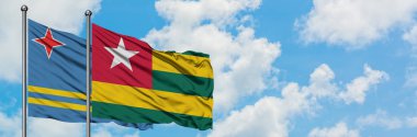 Aruba ve Togo bayrağı birlikte beyaz bulutlu mavi gökyüzüne karşı rüzgarda sallayarak. Diplomasi kavramı, uluslararası ilişkiler.