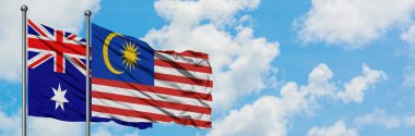 Avustralya ve Malezya bayrağı birlikte beyaz bulutlu mavi gökyüzüne karşı rüzgarda sallayarak. Diplomasi kavramı, uluslararası ilişkiler.