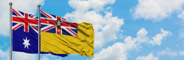 Avustralya ve Niue bayrağı birlikte beyaz bulutlu mavi gökyüzüne karşı rüzgarda sallayarak. Diplomasi kavramı, uluslararası ilişkiler.