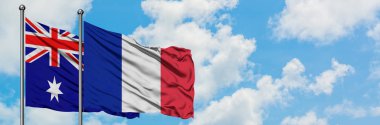 Avustralya ve Reunion bayrağı birlikte beyaz bulutlu mavi gökyüzüne karşı rüzgarda sallayarak. Diplomasi kavramı, uluslararası ilişkiler.