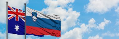 Avustralya ve Slovenya bayrağı birlikte beyaz bulutlu mavi gökyüzüne karşı rüzgarda sallayarak. Diplomasi kavramı, uluslararası ilişkiler.