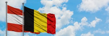Avusturya ve Belçika bayrağı birlikte beyaz bulutlu mavi gökyüzüne karşı rüzgarsal sallayarak. Diplomasi kavramı, uluslararası ilişkiler.