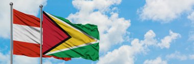 Avusturya ve Guyana bayrağı birlikte beyaz bulutlu mavi gökyüzüne karşı rüzgarda sallayarak. Diplomasi kavramı, uluslararası ilişkiler.
