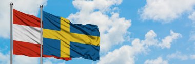 Avusturya ve İsveç bayrağı birlikte beyaz bulutlu mavi gökyüzüne karşı rüzgarsal sallayarak. Diplomasi kavramı, uluslararası ilişkiler.