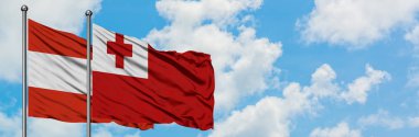 Avusturya ve Tonga bayrağı birlikte beyaz bulutlu mavi gökyüzüne karşı rüzgarda sallayarak. Diplomasi kavramı, uluslararası ilişkiler.