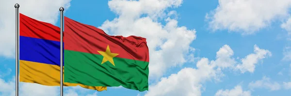 Bandera de Armenia y Burkina Faso ondeando en el viento contra el cielo azul nublado blanco juntos. Concepto diplomático, relaciones internacionales . — Foto de Stock
