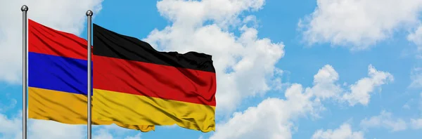 Armenien och Tyskland sjunker vifta i vinden mot vit grumlig blå himmel tillsammans. Diplomatisk koncept, internationella relationer. — Stockfoto