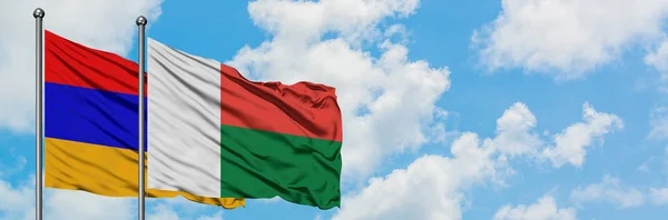 Drapeau de l'Arménie et de Madagascar agitant dans le vent contre le ciel bleu nuageux blanc ensemble. Concept de diplomatie, relations internationales . — Photo