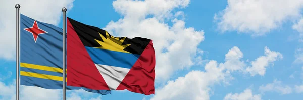 Aruba and Antigua and Barbuda flag waving in the wind against white cloudy blue sky together. Diplomacy concept, international relations. — Stock Photo, Image