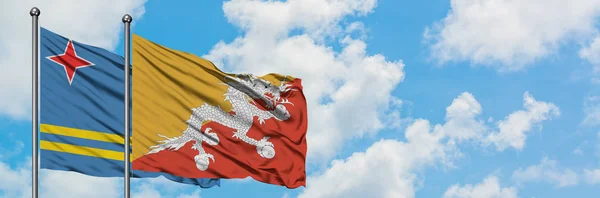 阿鲁巴和不丹国旗在风中飘扬，与白云相间的蓝天相一起。外交概念、国际关系. — 图库照片