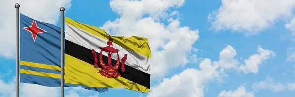 阿鲁巴和文莱国旗在风中飘扬，与白云相间的蓝天相一起。外交概念、国际关系. — 图库照片