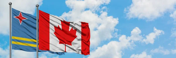 Bandera de Aruba y Canadá ondeando en el viento contra el cielo azul nublado blanco juntos. Concepto diplomático, relaciones internacionales . — Foto de Stock