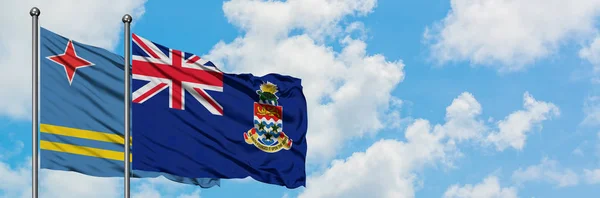 Αρούμπα και Νήσοι Κέιμαν σημαία που κουνώντας τον άνεμο ενάντια λευκό συννεφιασμένο γαλάζιο του ουρανού μαζί. Φιλοσοφία της διπλωματίας, διεθνείς σχέσεις. — Φωτογραφία Αρχείου