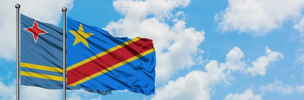 Bandera de Aruba y Congo ondeando en el viento contra el cielo azul nublado blanco juntos. Concepto diplomático, relaciones internacionales . — Foto de Stock