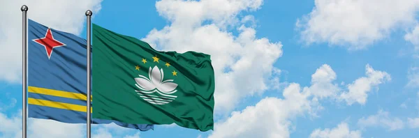 Aruba and Macao flag waving in the wind against white cloudy blue sky together. Diplomacy concept, international relations.