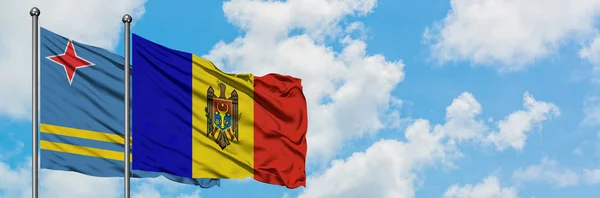 Bandera de Aruba y Moldavia ondeando en el viento contra el cielo azul nublado blanco juntos. Concepto diplomático, relaciones internacionales . — Foto de Stock