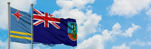 Aruba et le drapeau Montserrat agitant dans le vent contre ciel bleu nuageux blanc ensemble. Concept de diplomatie, relations internationales . — Photo