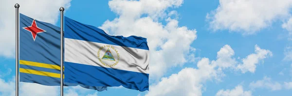 Aruba und nicaragua fahne wehen gemeinsam im wind vor weißem wolkenblauem himmel. Diplomatie-Konzept, internationale Beziehungen. — Stockfoto