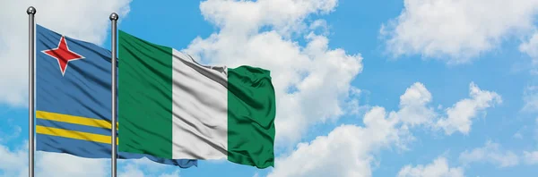 Aruba en Nigeria vlag zwaaien in de wind tegen witte bewolkte blauwe hemel samen. Diplomatie concept, internationale betrekkingen. — Stockfoto