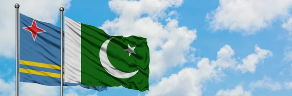 Bandera de Aruba y Pakistán ondeando en el viento contra el cielo azul nublado blanco juntos. Concepto diplomático, relaciones internacionales . — Foto de Stock