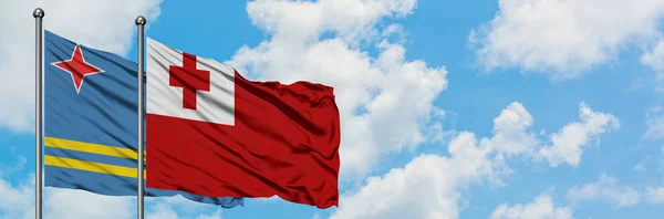 Bandera de Aruba y Tonga ondeando en el viento contra el cielo azul nublado blanco juntos. Concepto diplomático, relaciones internacionales . — Foto de Stock