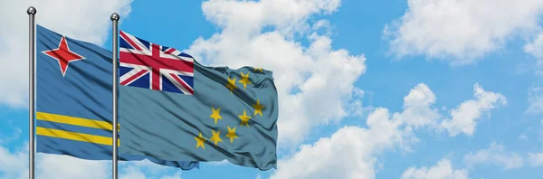 Bandera de Aruba y Tuvalu ondeando en el viento contra el cielo azul nublado blanco juntos. Concepto diplomático, relaciones internacionales . — Foto de Stock