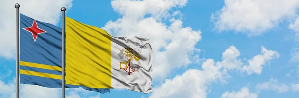 Aruba and Vatican City flag waving in the wind against white cloudy blue sky together. Diplomacy concept, international relations. — Stock Photo, Image