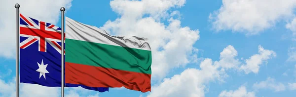 Bandera de Australia y Bulgaria ondeando en el viento contra el cielo azul nublado blanco juntos. Concepto diplomático, relaciones internacionales . — Foto de Stock