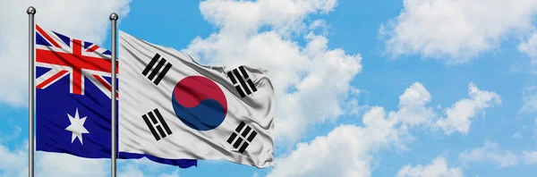 Bandera de Australia y Corea del Sur ondeando en el viento contra el cielo azul nublado blanco juntos. Concepto diplomático, relaciones internacionales . —  Fotos de Stock